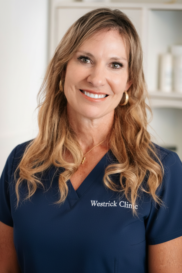 Westrick clinic westrick clinic smiling woman in navy scrubs with a clinic logo on her chest, standing in a medical office.